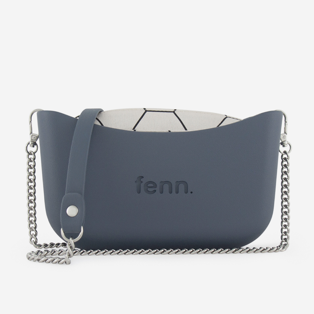 A slate blue fenn. shoulder bag with a curved silhouette, embossed logo on the front, a matching blue strap, and a silver chain strap, shown against a light gray background.