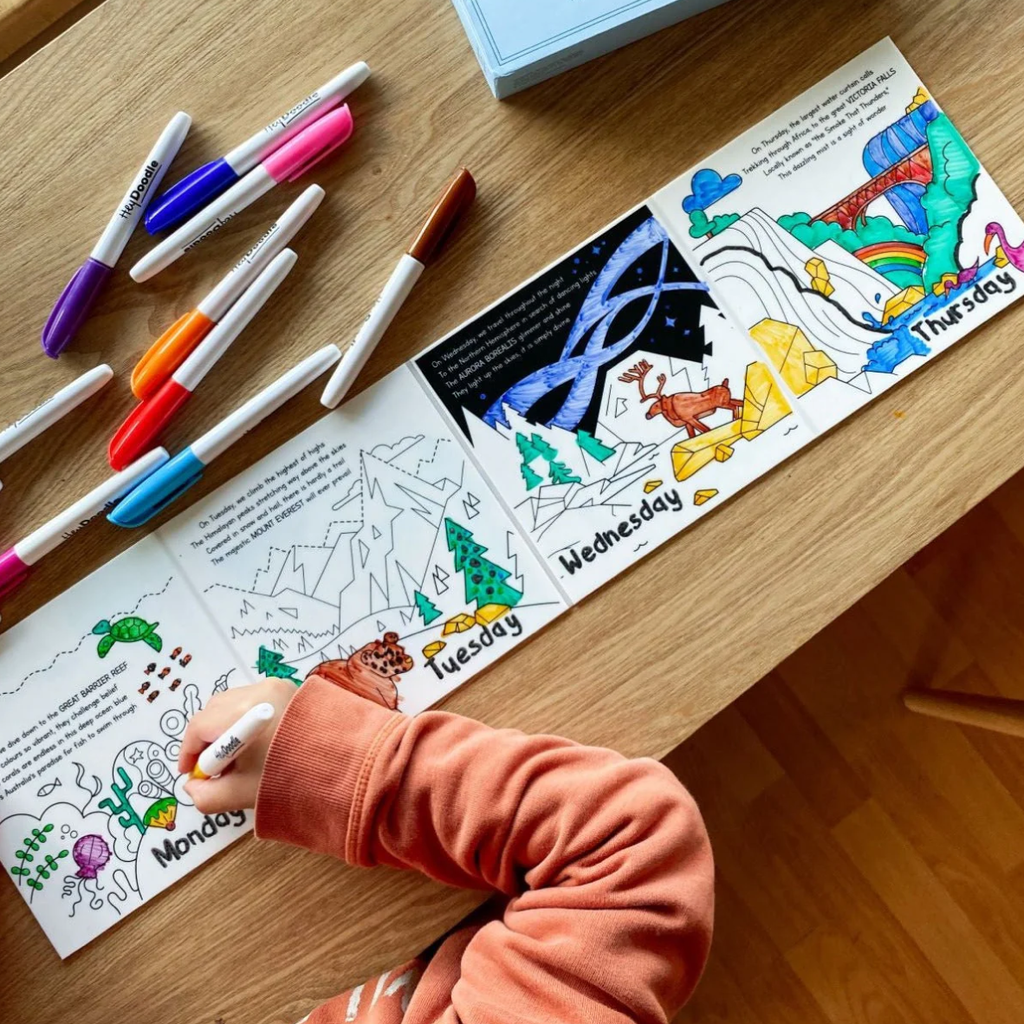 Coloring book with days of the week on a wooden table with markers.