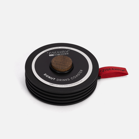 Stack of black drink coasters with a central donut-shaped coaster on a white background