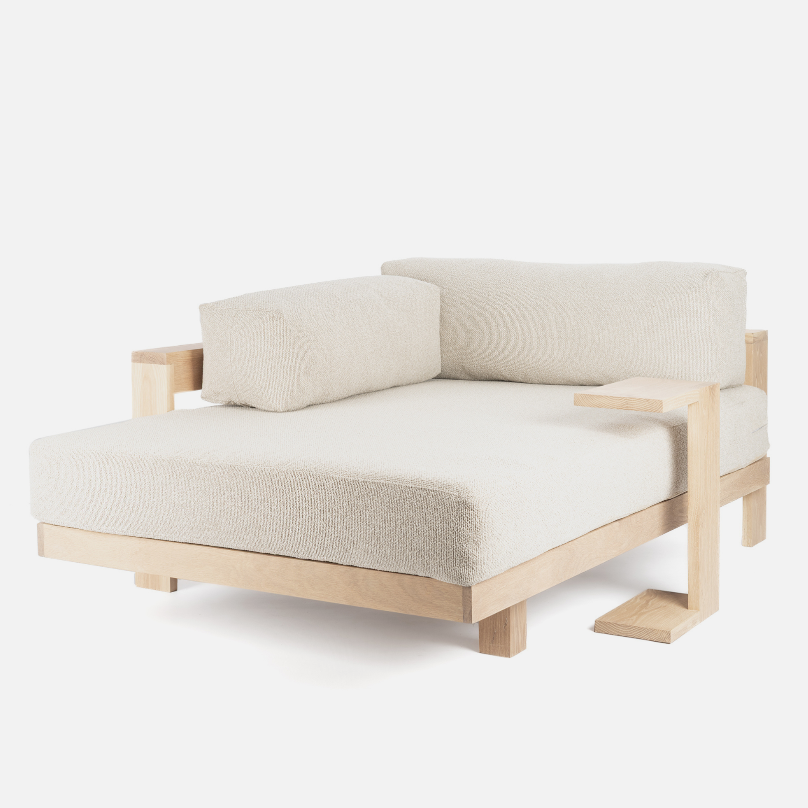 A minimalist L-shaped daybed with a light natural wood frame and thick, textured off-white cushions, shown against a plain white background.